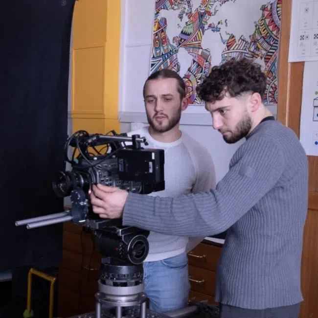 Mickaël et son acolyte en plein tournage en train de regarder les plans sur une grande caméra de tournage