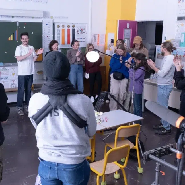 équipe de tournage applaudissant la fin de tournage dans une salle de classe